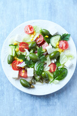 Simple Salad with Green Olives, Cucumber, Cherry Tomatoes and Capers. Bright wooden background. Top view.	