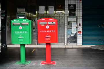 Taiwan - Mar 24, 2024: Taiwan's mailboxes come primarily in two colors: red for airmail and express delivery, and green for regular mail, with postal mailboxes in the background.