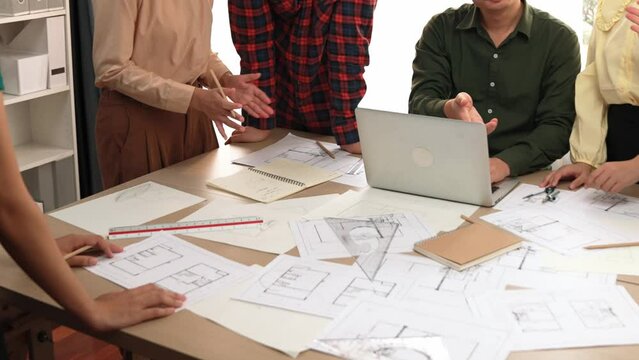 Architect and safety engineer celebrate success design building blueprint project on laptop on table with architectural document and wooden block scatter around at modern office. Closeup. Delineation.