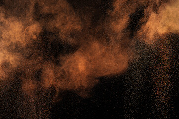 Brown grunge texture. Orange powder explosion on black background. Flame cloud. Yellow dust...