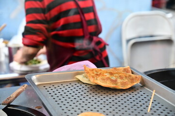 Close-up of a fried leek dumpling, a popular Northern Chinese and some Southern Chinese dish made with a filling of chives and a crispy egg-battered dough that is either pan-fried or baked.