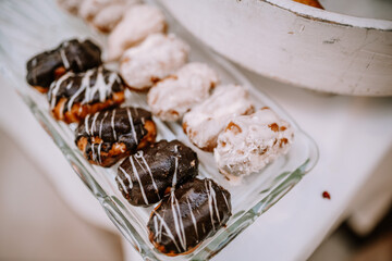 Valmiera, Latvia - August 19, 2023 - A glass tray filled with assorted eclairs, featuring chocolate...