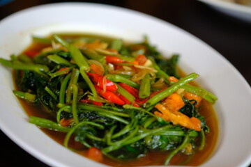 Tumis Kangkung (stir fry water spinach vegetable with chili and garlic), an Indonesian popular food. It can be found everywhere, in any province in Indonesia. Indonesian food. white plate. 