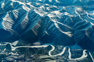 aerial view of snow capped mountain and winding frozen river