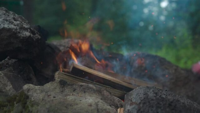 Campfire in the forest. Beautiful wooden campfire on fire between rocks, with particles of fire and ash. Camping, 4k video, close-up