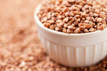 Uncooked, brown buckwheat grains in bowl. Dry buckwheat grains. Healthy food