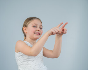 Little Caucasian girl having fun and pointing with fingers on white background. 