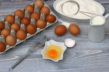 Baking ingredients eggs, milk and flour on a kitchen table.	.