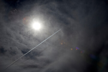 sun in the sky with clouds and condensation trails