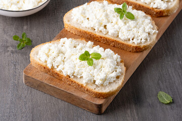 Bread with curd cheese on grey wooden table