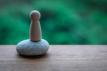 A minimalist puppet stands on a white pebble. Windowsill wood furnishings create artistic...