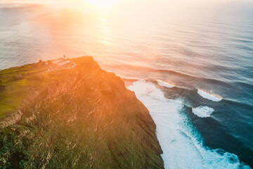 Aerial view of rough ocean with waves, volcanic beach, sunset over a huge cliff  in Lighthouse...
