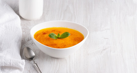 Pumpkin soup on a white wooden table, with copy space for text