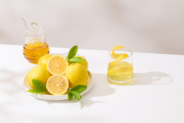 Lemon theme photo with some lemons featured on a round white dish, decorated by a jar of honey and...