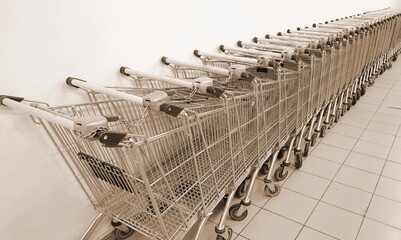 Grocery carts in a row against a white wall. Parking of grocery carts Sepia Filter