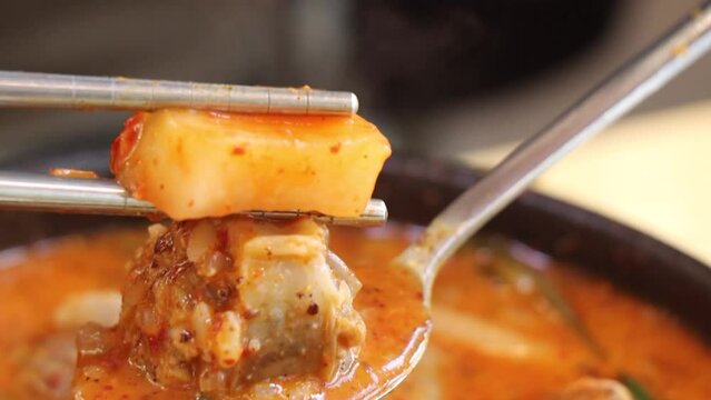 얼큰한 순대국밥에 깍두기 국물을 넣고 깍두기를 얹어 먹는 모습