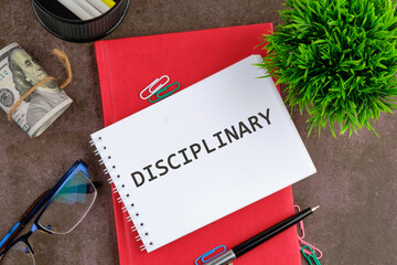 Showing DISCIPLINARY word on a blank sheet of notepad next to the business supplies