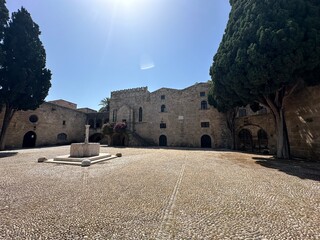 Old town square with fountain and ancient stone buildings at medieval city of Rhodes, Greece