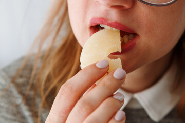 Close-up of a woman's mouth eating dried pineapple, a healthy snack for students.