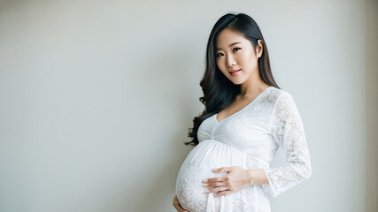 A beautiful asian pregnant woman in a maternity photography session. She looks peaceful and radiant as she poses elegantly.