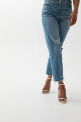 Vertical cropped portrait of young African woman in blue jeans posing over white wall.