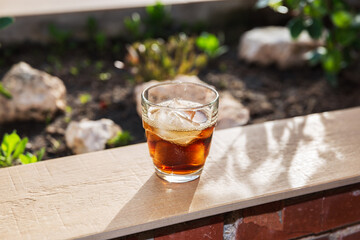 Glass filled with ice and a refreshing drink on a wallflower on the outdoor terrace on a summer...
