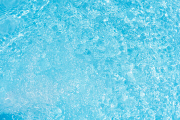 Blue water with ripples on the surface. Defocus blurred transparent blue colored clear calm water surface texture with splashes and bubbles. Water waves with shining pattern texture background.