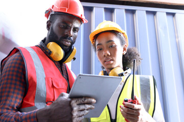 Two African workers wear safety vest and helmet at logistic shipping cargo containers yard. Happy...
