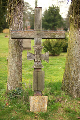 Ancient and weathered wooden cross on a cemetery in Germany, with an iron cross emblem