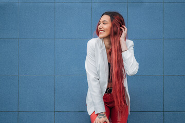 young woman or girl smiling redhead in hipster urban style smiling on the street leaning on the wall