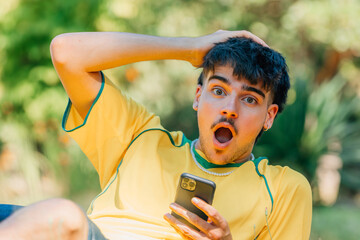 young man with mobile phone with surprised expression in the field