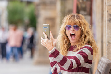 middle age adult woman on the street with mobile phone with expression of amazement or surprise