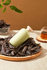 A pile of black locust fruits featured on a wooden dish with an unbranded bottle placed on top....