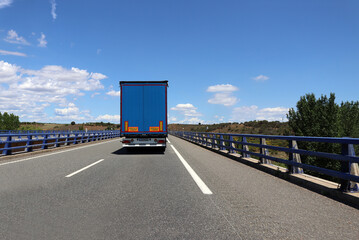 Blue lorry on motorway against blue sky on a sunny day