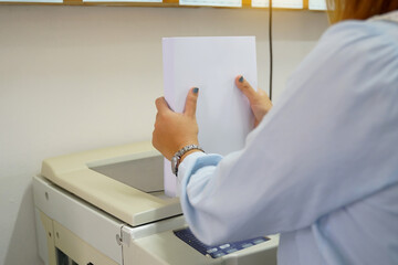 The secretary prepares paper to load into the copy machine tray. soft and selective focus.