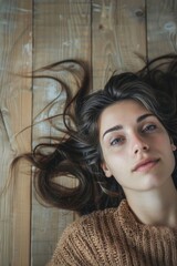 Fototapeta premium Woman laying on wooden floor with hair blowing in the wind. Suitable for lifestyle and beauty concepts