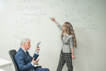Female student answers a question from an elderly professor at a white board. 