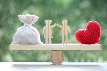 Love couple with money bag and red heart on wood scale seesaw on natural green background,Save...