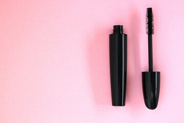 a tube of mascara on a pink background. Mascara brush on the background. A place for a makeup...