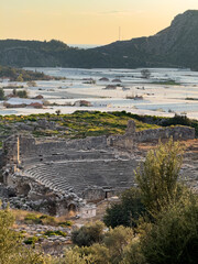 Fototapeta premium The ancient theatre of Xanthos in Kaş, Antalya, bathed in morning light with surrounding green landscape.
