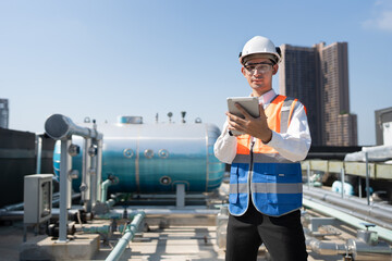 Portrait Asia male engineer in protective workwear is performing a conducts system check with use tablet computer at rooftop building	