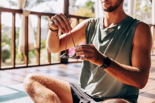 Midsection of man holding Tibetan bells while sitting at wellness resort