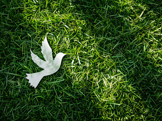 Cut paper with bird logo (pigeon) on green grass background. Peace sign and symbol background banner template of peace concept