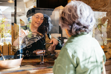 Woman Serving a Delicious Slice of Chocolate Cake to a Customer at a Takeaway Food Shop Counter