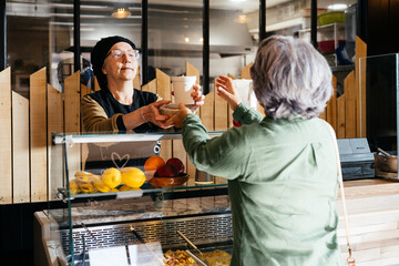 Senior Woman Purchasing Takeaway Food From Local Deli Counter During Lunchtime