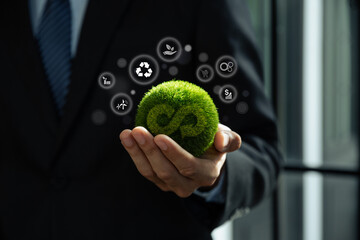 Hand of businessman holding green globe with circular economy icons, Circulating in an endless...