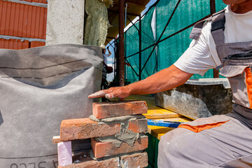 Worker is building wall of brick of building under construction