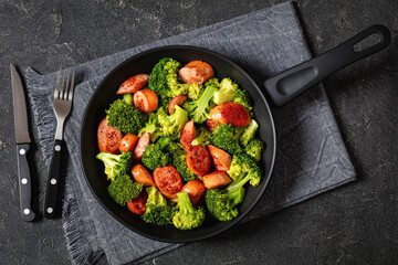 fried juicy sausage and crispy broccoli in skillet