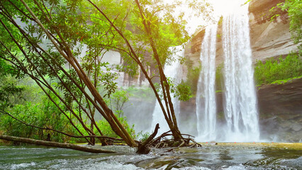 Jaw-dropping waterfall cascading from towering cliff, embraced by vibrant tropical greenery. Huai...