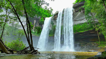 A breathtaking tropical waterfall cascading from a towering cliff, an epic natural wonder. Huai Luang Waterfall, Phu Chong Na Yoi national park, Ubon Ratchathani Province, Thailand. Nature concept.
